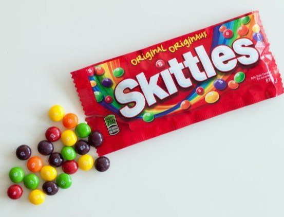 Skittles spilling from a torn bag