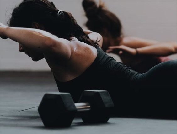 A floor workout mid-rep with dumbbells in the foreground