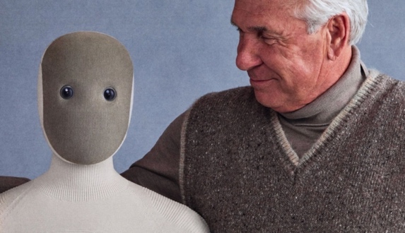 Fabric-faced 1X robot beside a smiling elderly man