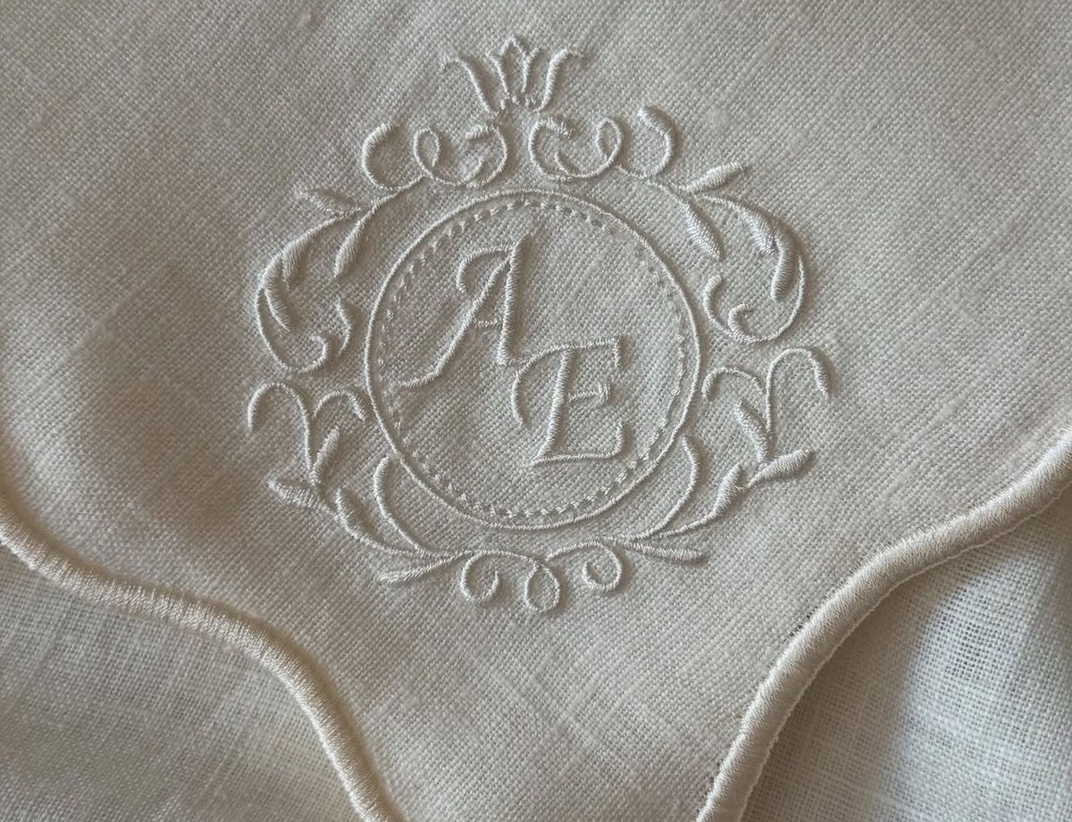 White-on-white embroidered cipher with ornamental flourish on linen