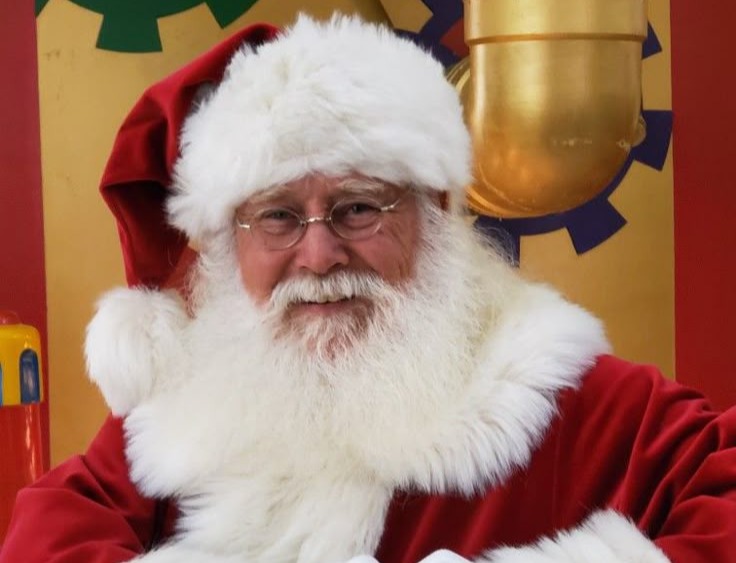 Mall Santa smiling in front of a gold backdrop