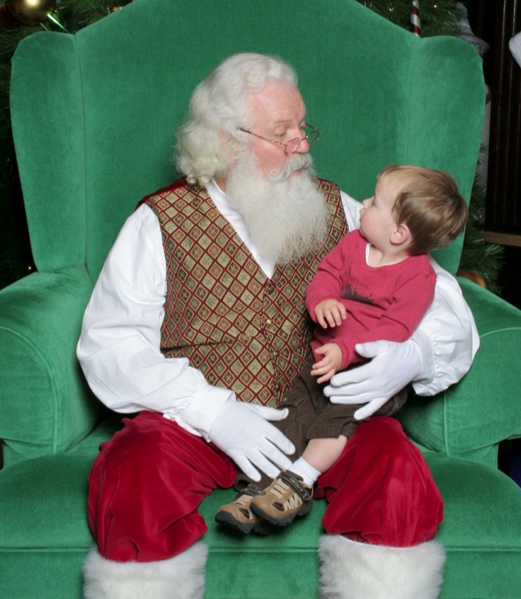 A real Santa holding a baby in a green studio chair