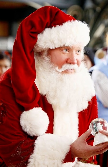 Hooded Santa outdoors holding an ornament